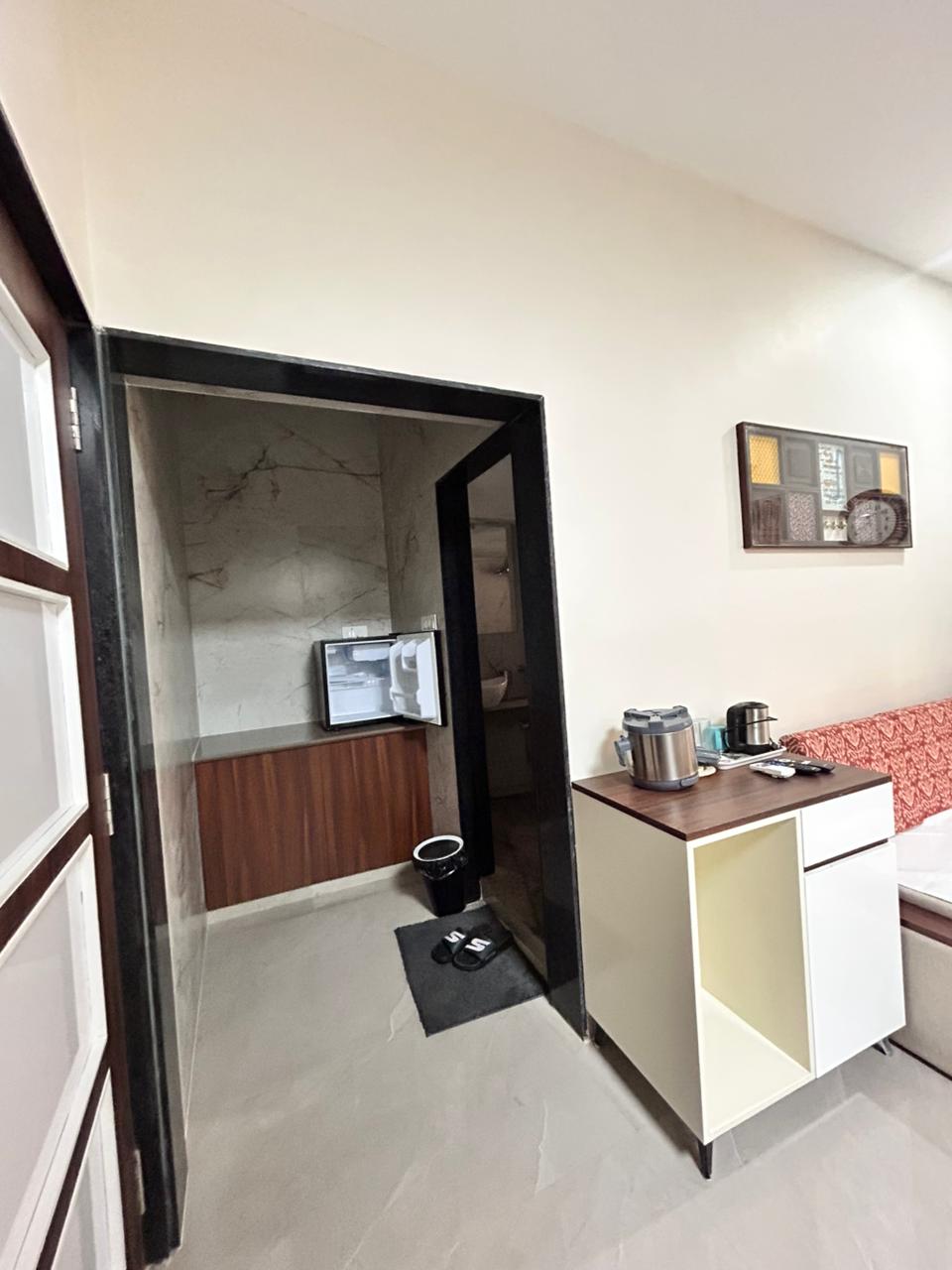 Room with wallpapered accent wall and tea kettle on console.