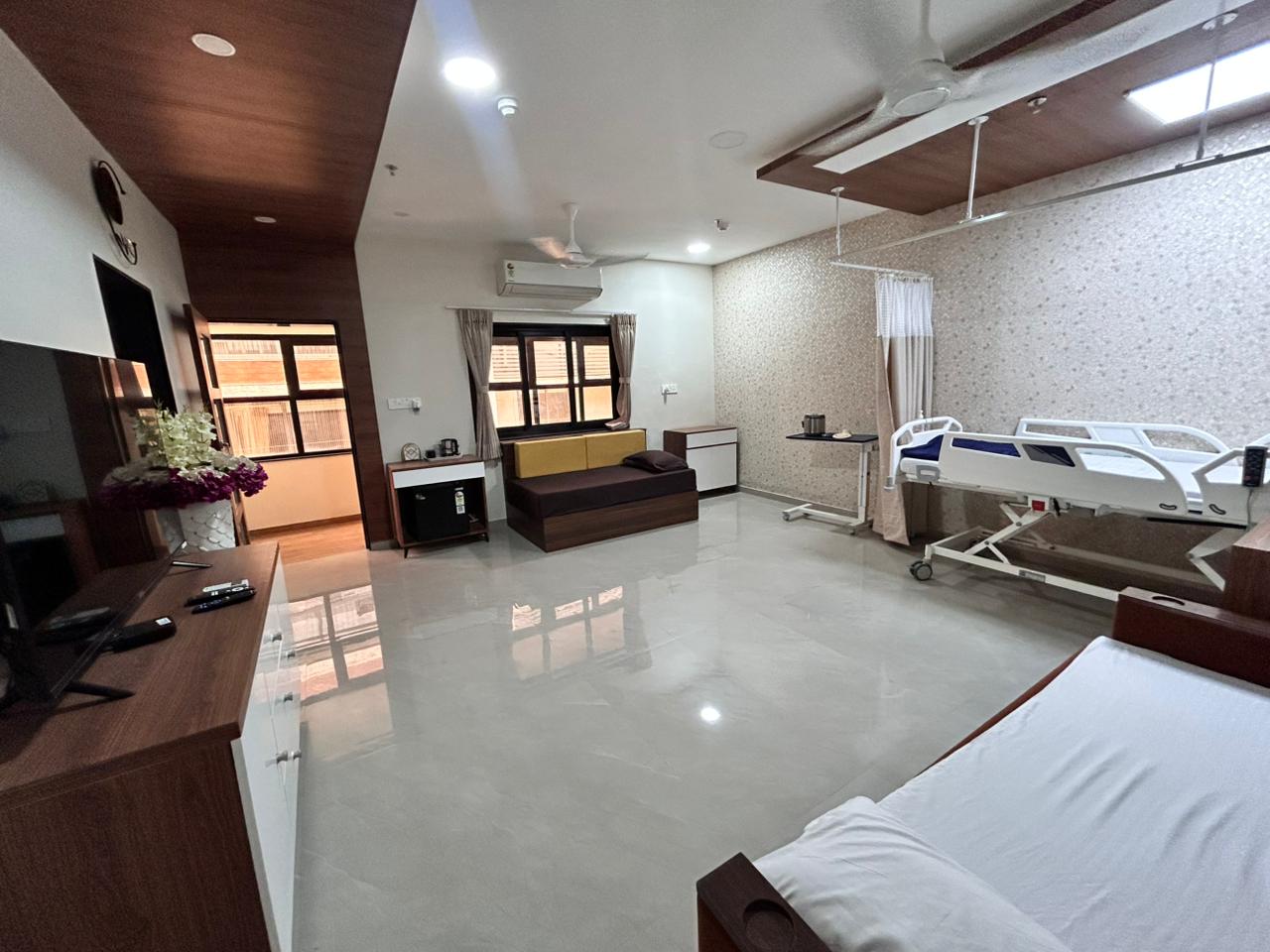 Wide view of patient room with bed, attendant sofa and entry.
